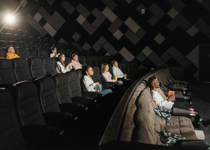 People enjoying a movie with snacks and comfortable seating in a premium theater